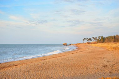 Gün batımında Baltık kıyıları (kum tepeleri). Yumuşak güneş ışığı, berrak gökyüzü, parlayan bulutlar, dalgalar. Idyllic deniz manzarası. Ziemelu Mols, Liepaja, Letonya, Avrupa. Seyahat yerleri, eko-turizm, doğa