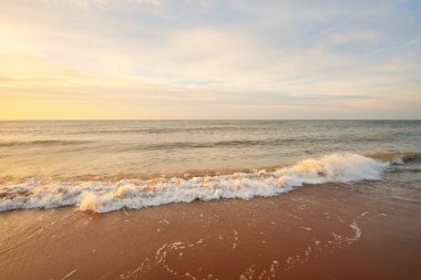 Gün batımında Baltık kıyıları (kum tepeleri). Yumuşak güneş ışığı, parlayan bulutlar, dalgalar ve su fışkıran berrak gökyüzü. Idyllic deniz manzarası. Liepaja, Letonya, Avrupa. Sıcak kış havası, iklim değişikliği, doğa