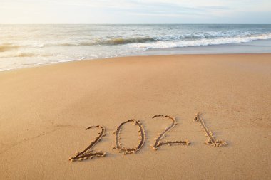 2021 numara, gün batımında kumlu sahilde, yakın plan. Yeni yıl kutlaması konsepti. Idyllic panoramik deniz manzarası. Yumuşak güneş ışığı. Kum, deniz suyu yüzeyi ve dalga dokusu. Grafiksel kaynaklar, alanı kopyala