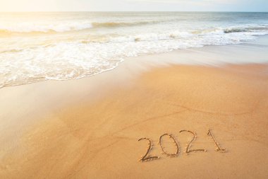 2021 numara, gün batımında kumlu sahilde, yakın plan. Yeni yıl kutlaması konsepti. Idyllic panoramik deniz manzarası. Yumuşak güneş ışığı. Kum, deniz suyu yüzeyi ve dalga dokusu. Grafiksel kaynaklar, alanı kopyala
