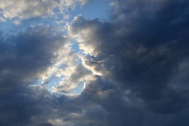 Destansı fırtına bulutları. Beyaz süslemeli günbatımı kümülüs bulutları. Yumuşak güneş ışığı, güneş ışınları. Açık mavi gökyüzü. Doğal desen, doku, arkaplan, duvar kağıdı, 3D, grafik kaynakları, tasarım, kopyalama alanı