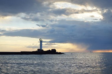 Güneş pilli deniz feneri. Baltık Denizi. Fırtınadan sonra dramatik günbatımı gökyüzü. Parlayan bulutlar, altın güneş ışığı. Umut ve barışın sembolü. Mimarlık, seyahat yerleri, navigasyon, yelkencilik.