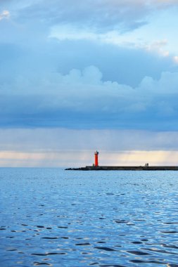 Güneş pilli deniz feneri. Baltık Denizi. Fırtınadan sonra dramatik günbatımı gökyüzü. Parlayan bulutlar, altın güneş ışığı. Umut ve barışın sembolü. Mimarlık, seyahat yerleri, navigasyon, yelkencilik.