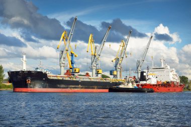 Kargo gemileri iskele terminaline yükleniyor. Vinçler arka planda. Baltık Denizi. Bunkering, akaryakıt ve enerji üretimi, arz, teknoloji, lojistik, hizmet, sanayi, ticaret