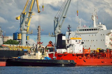 Kargo gemileri iskele terminaline yükleniyor. Vinçler arka planda. Baltık Denizi. Bunkering, akaryakıt ve enerji üretimi, arz, teknoloji, lojistik, hizmet, sanayi, ticaret