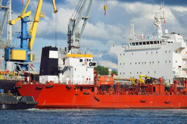 Kargo gemileri iskele terminaline yükleniyor. Vinçler arka planda. Baltık Denizi. Bunkering, akaryakıt ve enerji üretimi, arz, teknoloji, lojistik, hizmet, sanayi, ticaret