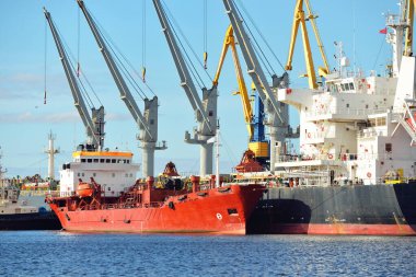 Kargo gemileri iskele terminaline yükleniyor. Vinçler arka planda. Baltık Denizi. Bunkering, akaryakıt ve enerji üretimi, arz, teknoloji, lojistik, hizmet, sanayi, ticaret