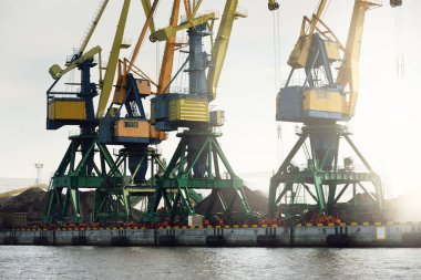 Riga, Letonya 'daki modern kömür terminali. Vinçler yakın plan. Baltık Denizi. Nakliye, lojistik, küresel iletişim, ekonomi, iş, endüstri, tedarik, özel ekipman. Şehir manzarası