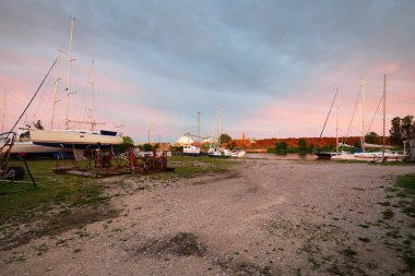Günbatımında yat limanında duran zarif ve modern yelkenliler. Dramatik gökyüzü, parlayan altın bulutlar. Tatiller, ulaşım, spor, eğlence, turizm, seyahat, liman
