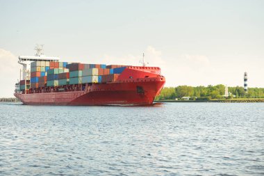Konteyner gemisi (168 metre uzunluğunda) gün batımında limandan ayrılıyor. Baltık Denizi. Yük taşımacılığı, lojistik, küresel iletişim, dünya çapında taşımacılık, ekonomi, iş dünyası, sanayi