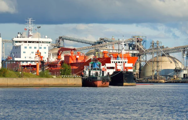 貨物港ターミナルに停泊する大型タンカーや小型船 背景にミネラル肥料の貯蔵とクレーン 貨物輸送 燃料および発電 — ストック写真