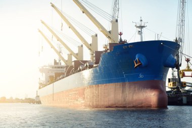 Büyük kargo gemisi (toplu taşıyıcı, 187 metre uzunluğunda) iskele terminalinde yükleme, arka planda vinçler. Yük taşımacılığı, lojistik, küresel iletişim, ekonomi, ticaret, sanayi