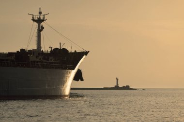 Vinçleri olan büyük bir kargo gemisi gün batımında limandan ayrılıyor. Baltık Denizi. Dramatik fırtına gökyüzü. Yük taşımacılığı, lojistik, küresel iletişim, ekonomi, ticaret, sanayi