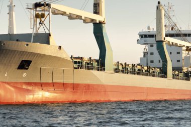 Gün batımında açık denizde yelken açan büyük bir yük vinci gemisi. Altın güneş ışığı. Yük taşımacılığı, deniz taşımacılığı, lojistik, küresel iletişim, ekonomi, iş dünyası, sanayi, dünya çapında nakliye