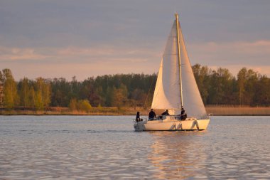 Baltık Denizi 'nde yelkenli bir yat. Gün batımı. Fırtınadan sonra dramatik bir gökyüzü, altın güneş ışığı. Ulaşım, seyahat, gezi, yat yarışı, spor, eğlence, boş zaman aktivitesi, yaşam tarzı