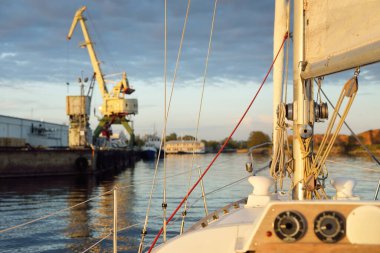 Beyaz yat gün batımında limana varacak. Güverteden pruva ve yelkenlere kadar yakın çekim. Fırtınadan sonra dramatik bir gökyüzü. Baltık Denizi. Deniz aracı, ulaşım, hizmet, spor, eğlence kavramları