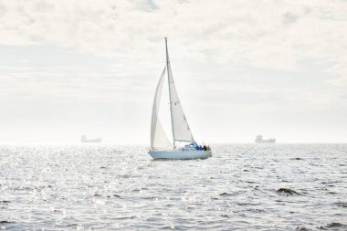 Açık denizde yelkenli yelkenli yelkenli. Gökyüzü açık, bulutlu. Yelkenlinin manzarası. Ulaşım, seyahat, spor, eğlence, boş zaman aktivitesi, yarış, yelkenli yarışı. Panorama, boşluğu kopyala