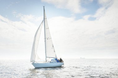 Açık denizde yelkenli yelkenli yelkenli. Gökyüzü açık, bulutlu. Yelkenlinin manzarası. Ulaşım, seyahat, spor, eğlence, boş zaman aktivitesi, yarış, yelkenli yarışı. Panorama, boşluğu kopyala