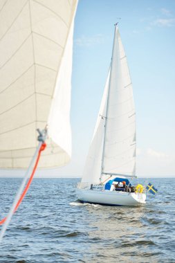 Açık denizde yelkenli yelkenli yelkenli. Gökyüzü açık, bulutlu. Yelkenlinin manzarası. Ulaşım, seyahat, spor, eğlence, boş zaman aktivitesi, yarış, yelkenli yarışı. Panorama, boşluğu kopyala