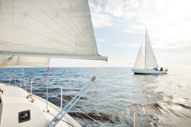 Açık denizde yelkenli yelkenli yelkenli. Gökyüzü açık, bulutlu. Yelkenlinin manzarası. Ulaşım, seyahat, spor, eğlence, boş zaman aktivitesi, yarış, yelkenli yarışı. Panorama, boşluğu kopyala