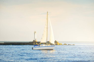Günbatımında Baltık Denizi 'nde yelkenli yelkenli yelkenli. Fırtınadan sonra açık gökyüzü, yumuşak güneş ışığı. Deniz feneri. Ulaşım, seyahat, gezi, spor, eğlence, boş zaman aktivitesi, yarış, yelkenli yarışı
