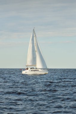 Baltık Denizi 'nde yelkenli bir yat. Gün batımı. Fırtınadan sonra dramatik bir gökyüzü, yumuşak güneş ışığı. Ulaşım, seyahat, seyahat, yat yarışı, spor, eğlence, eğlence, eğlence, yaşam tarzı, aile.