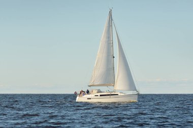 Baltık Denizi 'nde yelkenli bir yat. Gün batımı. Fırtınadan sonra dramatik bir gökyüzü, yumuşak güneş ışığı. Ulaşım, seyahat, seyahat, yat yarışı, spor, eğlence, eğlence, eğlence, yaşam tarzı, aile.
