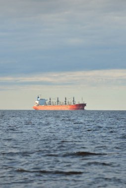 Büyük kırmızı bir yük gemisi (179 metre uzunluğunda) açık bir Baltık Denizi 'nde yüzüyor. Dramatik bir gökyüzü. Yük taşımacılığı, denizcilik gemisi, lojistik, küresel iletişim, ekonomi, iş dünyası, sanayi