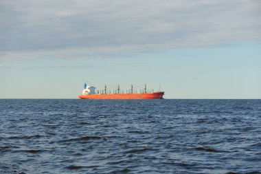 Büyük kırmızı bir yük gemisi (179 metre uzunluğunda) açık bir Baltık Denizi 'nde yüzüyor. Dramatik bir gökyüzü. Yük taşımacılığı, denizcilik gemisi, lojistik, küresel iletişim, ekonomi, iş dünyası, sanayi