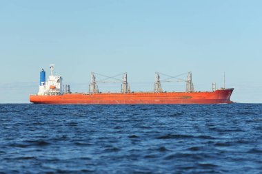 Büyük kırmızı bir yük gemisi (179 metre uzunluğunda) açık bir Baltık Denizi 'nde yüzüyor. Dramatik bir gökyüzü. Yük taşımacılığı, denizcilik gemisi, lojistik, küresel iletişim, ekonomi, iş dünyası, sanayi