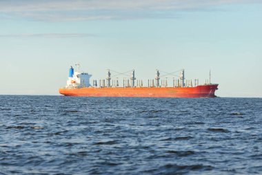 Büyük kırmızı bir yük gemisi (179 metre uzunluğunda) açık bir Baltık Denizi 'nde yüzüyor. Dramatik bir gökyüzü. Yük taşımacılığı, denizcilik gemisi, lojistik, küresel iletişim, ekonomi, iş dünyası, sanayi