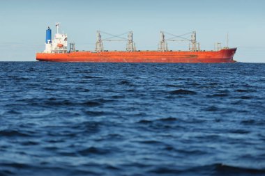 Büyük kırmızı bir yük gemisi (179 metre uzunluğunda) açık bir Baltık Denizi 'nde yüzüyor. Dramatik bir gökyüzü. Yük taşımacılığı, denizcilik gemisi, lojistik, küresel iletişim, ekonomi, iş dünyası, sanayi