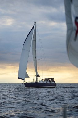 Baltık Denizi 'nde yelkenli bir yat. Gün batımı. Fırtınadan sonra dramatik bir gökyüzü, altın güneş ışığı. Ulaşım, seyahat, gezi, yat yarışı, spor, eğlence, boş zaman aktivitesi, yaşam tarzı