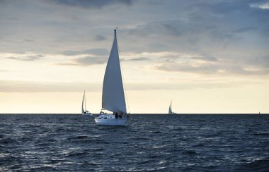 Baltık Denizi 'nde yelkenli bir yat. Gün batımı. Fırtınadan sonra dramatik bir gökyüzü, altın güneş ışığı. Ulaşım, seyahat, gezi, yat yarışı, spor, eğlence, boş zaman aktivitesi, yaşam tarzı