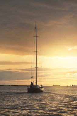 Baltık Denizi 'nde yelkenli bir yat. Gün batımı. Fırtınadan sonra dramatik bir gökyüzü, altın güneş ışığı. Ulaşım, seyahat, gezi, yat yarışı, spor, eğlence, boş zaman aktivitesi, yaşam tarzı