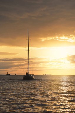 Baltık Denizi 'nde yelkenli bir yat. Gün batımı. Fırtınadan sonra dramatik bir gökyüzü, altın güneş ışığı. Ulaşım, seyahat, gezi, yat yarışı, spor, eğlence, boş zaman aktivitesi, yaşam tarzı