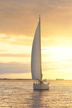 Baltık Denizi 'nde yelkenli bir yat. Gün batımı. Fırtınadan sonra dramatik bir gökyüzü, altın güneş ışığı. Ulaşım, seyahat, gezi, yat yarışı, spor, eğlence, boş zaman aktivitesi, yaşam tarzı