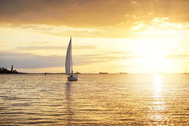 Baltık Denizi 'nde yelkenli bir yat. Gün batımı. Fırtınadan sonra dramatik bir gökyüzü, altın güneş ışığı. Ulaşım, seyahat, gezi, yat yarışı, spor, eğlence, boş zaman aktivitesi, yaşam tarzı