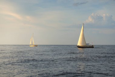 Baltık Denizi 'nde yelkenli bir yat. Gün batımı. Fırtınadan sonra dramatik bir gökyüzü, yumuşak güneş ışığı. Ulaşım, seyahat, seyahat, yat yarışı, spor, eğlence, eğlence, eğlence, yaşam tarzı, aile.