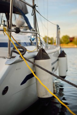 Yelkenliler açık bir yaz gününde yat limanındaki bir rıhtıma demirlediler. Tekne çamurlukları yakın plan. Ekipman, ulaşım, eğlence, tatil, boş zaman aktivitesi, spor, gezi, yaşam tarzı