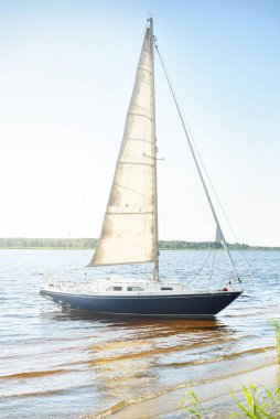 Kumlu kıyıya demirli mavi şalopeli yat (kumsalda otlarla kaplanmış). İsveç 'te, Avrupa' da. Doğa, yaz tatilleri, eğlence, gezi, spor, ulaşım. Hava görünümü