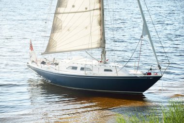 Kumlu kıyıya demirli mavi şalopeli yat (kumsalda otlarla kaplanmış). İsveç 'te, Avrupa' da. Doğa, yaz tatilleri, eğlence, gezi, spor, ulaşım. Hava görünümü