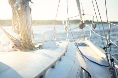 Açık bir günde beyaz yelkenli tekneyle denize açılmak. Güverteden direğe kadar bir manzara. Ekipmanlar, ipler, yakın çekim. Ulaşım, seyahat, gezi, eğlence, eğlence, eğlence, yat yarışı.