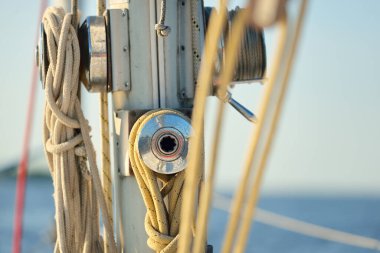 Açık bir günde beyaz yelkenli tekneyle denize açılmak. Güverteden direğe kadar bir manzara. Ekipmanlar, ipler, yakın çekim. Ulaşım, seyahat, gezi, eğlence, eğlence, eğlence, yat yarışı.