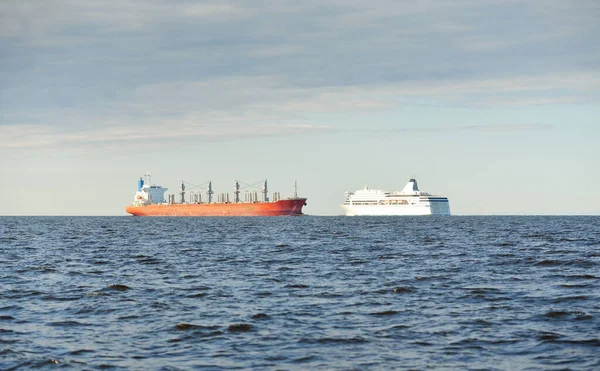 オープンバルト海で大規模な赤いばら積み貨物船 179メートルの長さ と白いクルーズ船 ライナー セーリング 劇的な空だ 貨物輸送 旅客輸送 — ストック写真