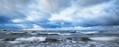 Kışın Baltık Denizi 'nin üzerindeki fırtına bulutları, uzun pozlama. Dramatik günbatımı gökyüzü, dalgalar ve su sıçramaları. Koyu deniz manzarası. Almanya