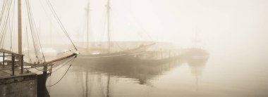 Zarif ve modern yatlar, yelkenli ve balıkçı tekneleri sisli bir iskelede demirlemişti. Schooner yakın plan. Manzaralar, turistik yerler, eski liman, tarih, geçmiş. Sepia görüntü efekti. Germaniahafen, Kiel, Almanya