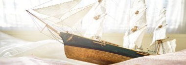 Retro stili altın antika pusula (güneş saati), ahşap uzun gemi ölçeği modeli ve eski beyaz deniz haritası yakın plan. Klasik natürmort. Yelkencilik, seyahat, yön bulma kavramları. Koleksiyon, hatıra, hediye.