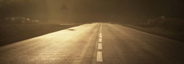 Sıcak bir yaz gününde gün batımında açık bir otoyol. Arka planda orman var. Kırsal alanlarda araba sürmek. Boş zaman aktivitesi, eğlence teması. Letonya