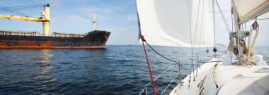 Cebelitarık Boğazı 'nda demirli büyük siyah yük vinci gemisi. Yat manzaralı, beyaz yelkenliler yakın çekim. Yaz Atlantik 'i İspanya ve Afrika' ya doğru gidiyor. Açık mavi gökyüzü